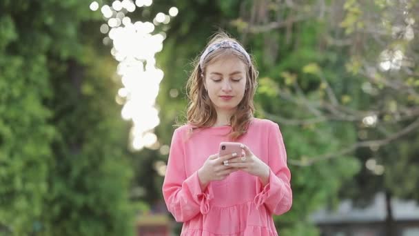 Perfil de una chica seria usando teléfono móvil en un parque . Video de stock libre de derechos