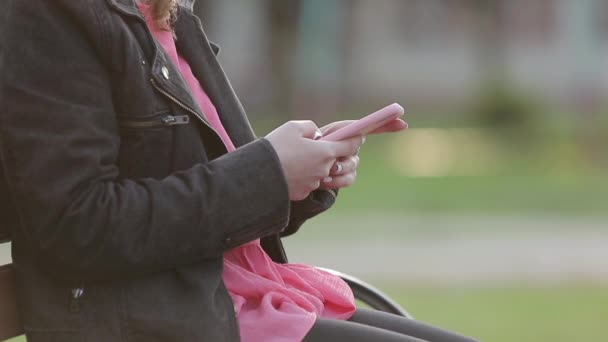 Siyah ceketli kız caddede yürürken cep telefonuna bakıyor.. Stok Video