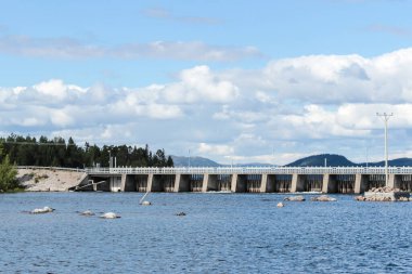 Arkasında dağlar olan hidroelektrik barajı.