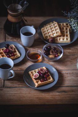 Ahşap sehpa üzerinde kahvaltı masası ayarı. Waffle, kahve zamanı.