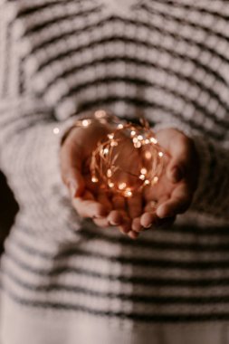 Kadın elinde bakır yaylı ışık. Noel havası ve atmosferi. Bulanık fotoğraflar, bokeh.