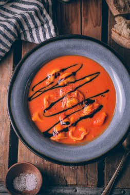 Ev yapımı peynir tortellini ile Sonbahar kırmızı domates kremaçorbası ve balsamik azaltma ile tepesinde. Rustik tarzda çorba kase.