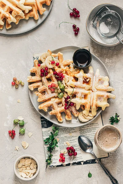 Krispiga Belgian våfflor med röda vinbär, krusbär, lönnsirap och pulveriserat socker på den grå keramiska plattan — Stockfoto