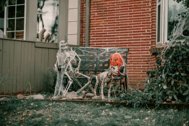 Korkunç ürkütücü Cadılar Bayramı evi dekorasyonları. Cadılar Bayramı sezonu. 31 Ekim ürkütücü bir gün. Şaka mı şeker mi çocuklar tatili mi? Korkunç cadı, hayalet, örümcekler, palyaço, balkabağı, iskelet dekoru. Tabut çimlerin üzerinde.