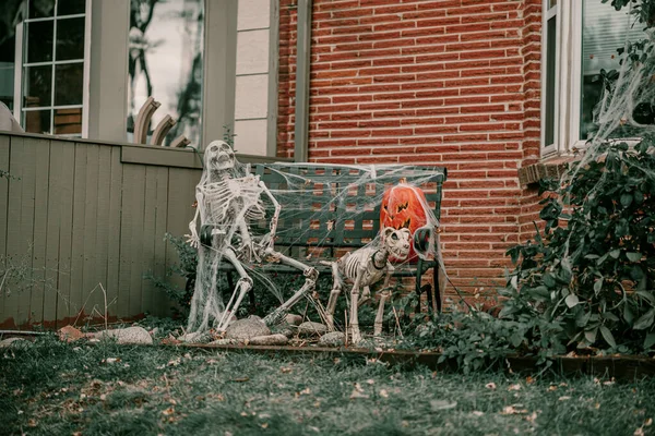 Scary spooky Halloween house decorations. Halloween season. October 31 spooky day. Trick or treat kids holiday. Scary witch, ghost, spiders, clown, pumpkins, skeleton decor. Coffin on the grass near t