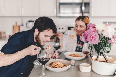 Aile yemeği. Makarna yemeği. Lezzetli yemek ve şarap. Öğle yemeğinde ne diyeceğini tartışıyor. Gülüyor, konuşuyor. Yiyeceklerle toplanıyor. Ev yemeği. Evde kal ve yemek yap. Ye, iç, gül..