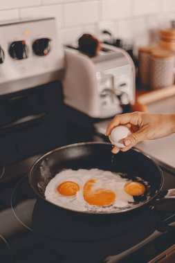 Kahvaltı hazırlığı. Sabah yemeği hazırlıyorum. Hafta içi rutini. Aile için çalışmadan önce yemek pişirmek. Yumurtaları tavaya kırıyorum. Ev hayatı. Kocanla kahvaltı. Fırın, tost makinesi. Seçici odak