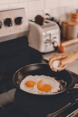 Kahvaltı hazırlığı. Sabah yemeği hazırlıyorum. Hafta içi rutini. Aile için çalışmadan önce yemek pişirmek. Yumurtaları tavaya kırıyorum. Ev hayatı. Kocanla kahvaltı. Fırın, tost makinesi. Seçici odak