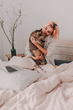 Genç bayan yatakta dinleniyor. İzin günü. Yatma vakti. Sabahın erken saatlerinde. Beyaz, bej, gri. Aydınlık ve parlak. Sabah ayini. Daire hayatı. Sıcak çarşaf. Yumuşak yastık ve yorgan.