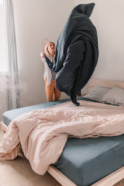 Молодая красивая женщина застилает постель. Свежее постельное белье. Надень наволочку. Светлая и светлая комната. Бежевый, белый, серый. Делаю домашнюю работу. Уборка и организация. Уютный дом. Живой
.