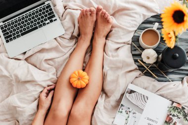 Kadın yatakta kahvenin tadını çıkarıyor. Laptop üzerinde çalışıyorum. Ayçiçeği aranjmanı. Yatak odası titreşimi. Sonbahar sezonu. Evimde gibi hissediyorum. Küçük şeylerden zevk alıyorum. Sonbahar renkleri ve havası. Evde çalış..