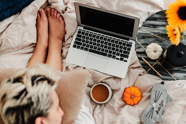 Woman is enjoying coffee in the bed. Working on the laptop. Sunflower arrangement. Bedroom vibe. Autumn season. Feeling home comfortable. Enjoying little things. Fall colors and mood. Work at home.