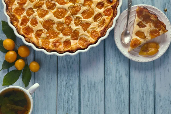 Deliciosa torta de ameixa de cereja em uma assadeira em uma mesa de madeira pintada de azul — Fotografia de Stock