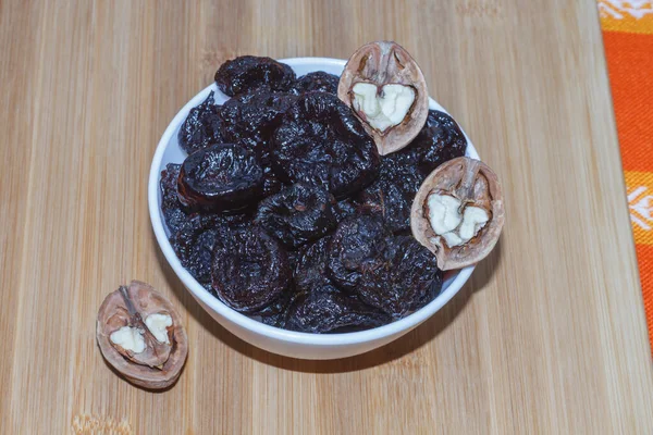  Kurutulmuş erik ve ceviz ile ahşap bir tahtanın üzerinde sağlıklı yiyecekler budar..