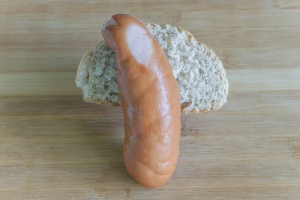 Çiğ sosis ve tahta üzerinde yakın plan bir parça ekmek.