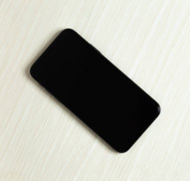 Beyaz masadaki kopyalama alanı olan siyah akıllı telefon.