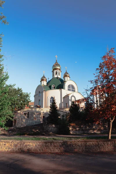 Eastern orthodox church covered by trees in day time on blue sky background