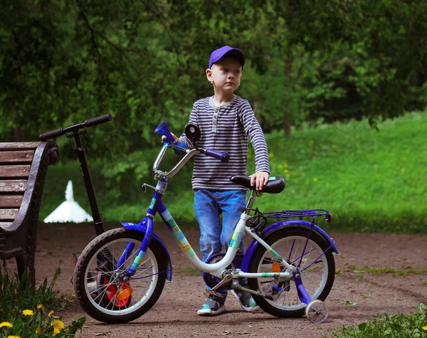 ジーンズとストライプのTシャツを着た男の子が自転車の近くに立っています — ストック写真