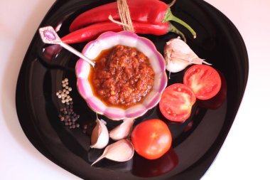 Domates sosu ve siyah bir tabak üzerinde malzemeler