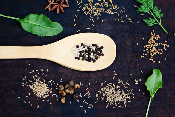 A spoonful of peppercorn on a cutting board with spices