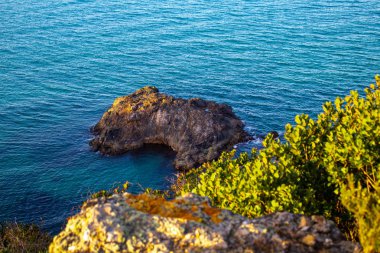 Denizin ortasında egzotik bir kaya. Denizlerle çevrili bir kaya parçası. Yüksek ve uzak görünüm 