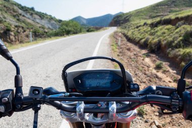 Asfalt yol kenarında motosiklet standı. Gösterge panelinin önünde uzun bir yol var. 