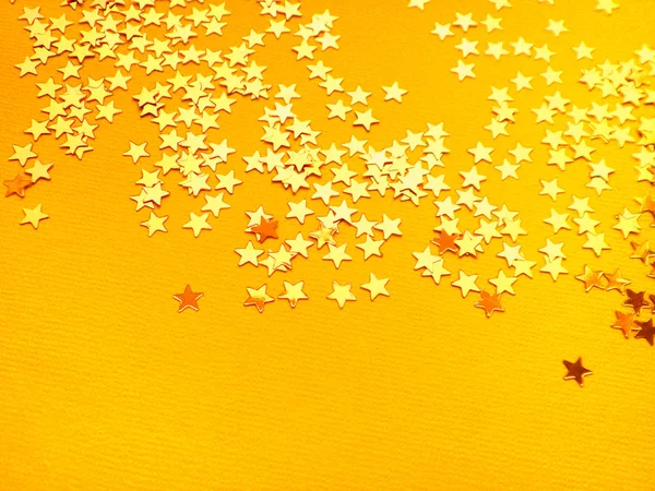 Estrelas douradas brilham no fundo de papel laranja — Fotografia de Stock