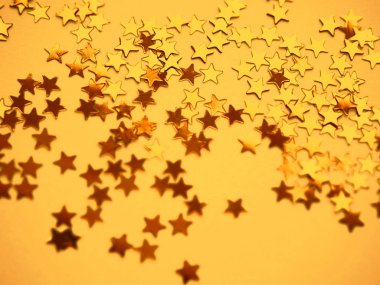 Altın yıldızlar sarı kağıt arka planda parlıyor