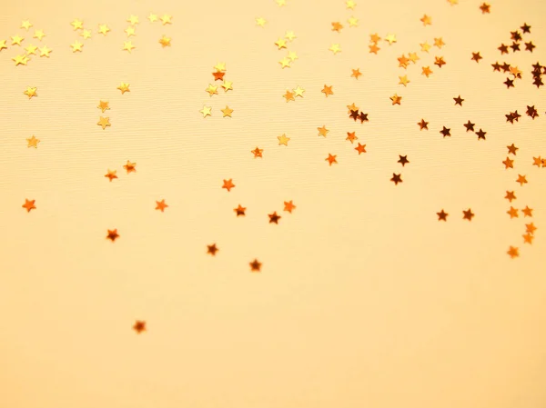 Altın yıldızlar sarı kağıt arka planda parlıyor — Stok fotoğraf