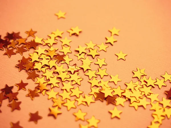 Arany csillagok csillognak narancssárga papír háttér — Stock Fotó