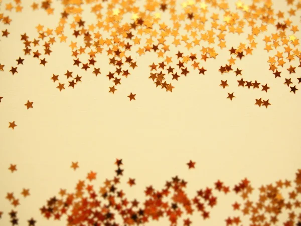 Golden stars glitter on yellow paper background — Stock Photo, Image