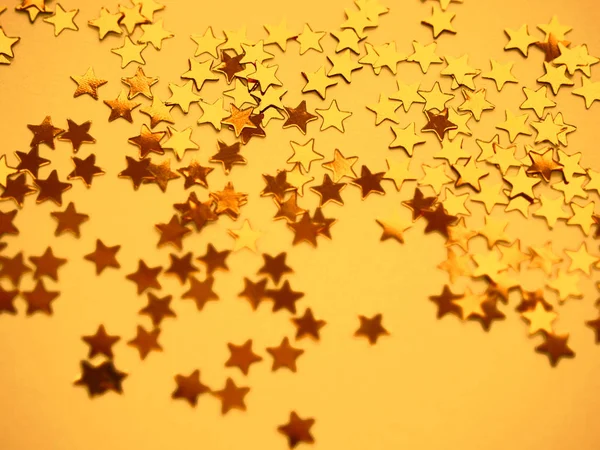 Golden stars glitter on yellow paper background