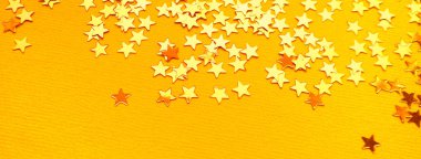 Altın yıldızlar turuncu kağıt arka planda parlıyor