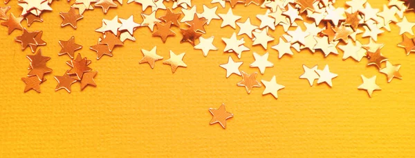 Estrelas douradas brilham no fundo de papel laranja — Fotografia de Stock