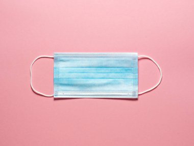 Pastel pembe arka planda tıbbi koruyucu maske. Bireysel, tek kullanımlık cerrahi maske. Karantina sağlık, hijyen ve koronavirüs koruma kavramı.