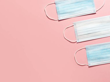 Pastel pembe arka planda tıbbi koruyucu maske. Bireysel, tek kullanımlık cerrahi maske düz desen. Karantina sağlık, hijyen ve koronavirüs koruma kavramı.