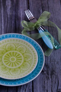 ahşap arka plan üzerine düzenlenmiş boş renkli tabak lar ve çatal bıçak takımı