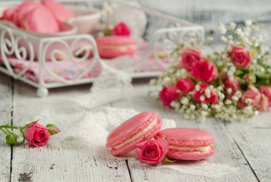 Vanilya macarons ahşap arka plan üzerinde pembe güllü