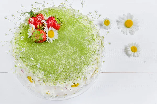 Sponge cake with strawberries and matcha tea on wooden table