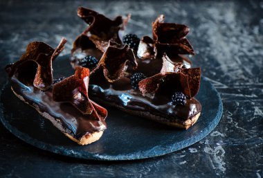 Çikolata choux pasta, çikolata parçalamak, krem karamel siyah çikolata, fasulyeli ince chantilly, ekstra siyah sır ve gevrek çikolata gevreği ile