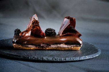 Çikolata choux pasta, çikolata parçalamak, krem karamel siyah çikolata, fasulyeli ince chantilly, ekstra siyah sır ve gevrek çikolata gevreği ile