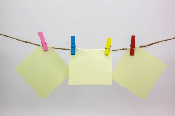 There are three yellow notes on the rope. They pinned by color small clothespins. Background is white