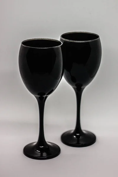 Black glasses for wine on the white background. Contrasting photo