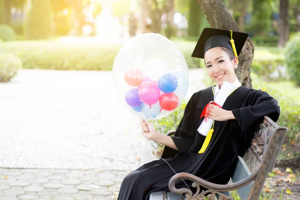Portrait of happy young female graduates in academic dress and s