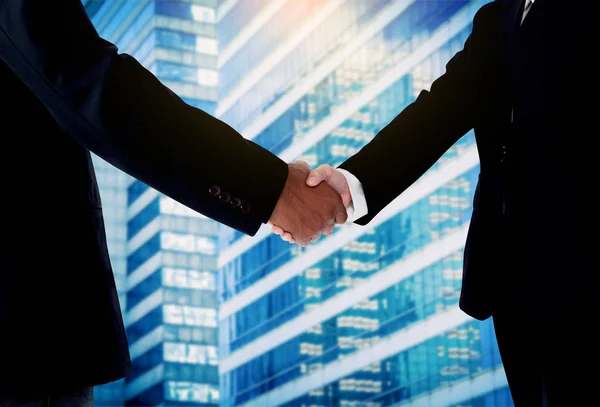 Hand shake between a businessman and a businesswoman with buildi — Stock Photo, Image