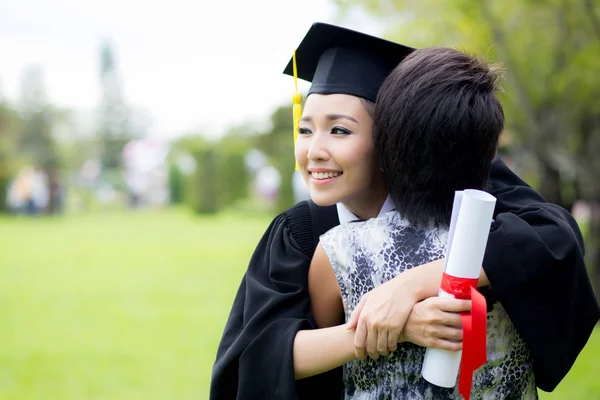 Mladá samice absolvent objímání její přítel na promoce — Stock fotografie