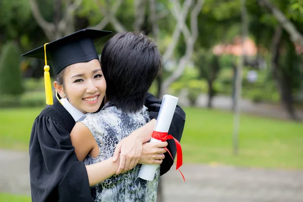 Jovem graduado abraçando seu amigo na cerimônia de formatura — Fotografia de Stock