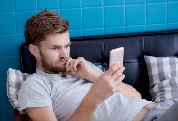 Happy Man oglądania treści multimedialnych w inteligentny telefon siedzi na c — Zdjęcie stockowe