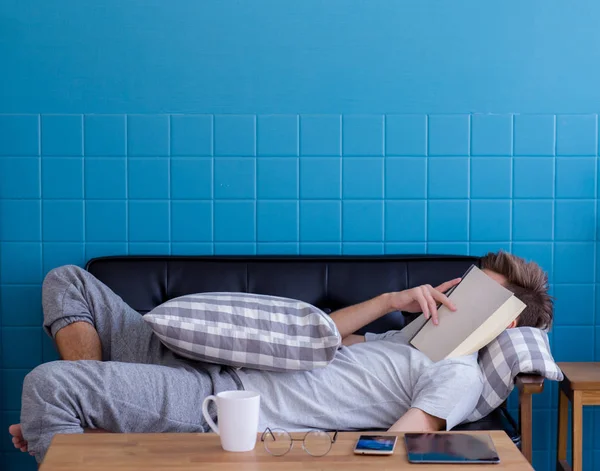 Uomo che dorme sul vecchio divano con libro che si copre il viso perché rea — Foto Stock