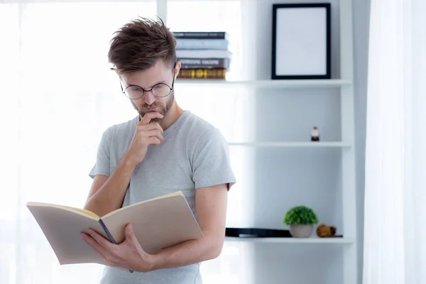 Bello ragazzo in occhiali sta leggendo libro preparazione esame con s — Foto Stock